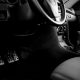 Interior de carro manual com volante, câmbio e pedais, incluindo o pedal da embreagem.