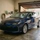 Toyota Corolla Hybrid azul estacionado em garagem residencial.
