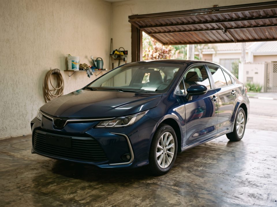 Toyota Corolla Hybrid azul estacionado em garagem residencial.