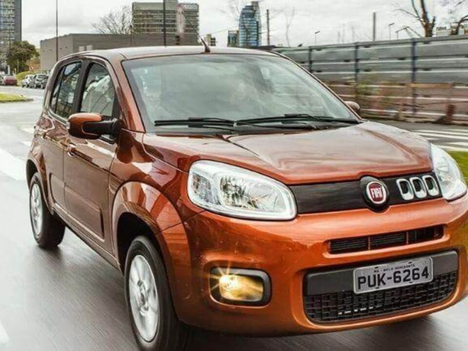 Fiat Uno em movimento na rua, visto de frente.