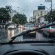 Foto feita de dentro do carro com palheta do limpador de para-brisa em funcionamento durante chuva intensa em via urbana.