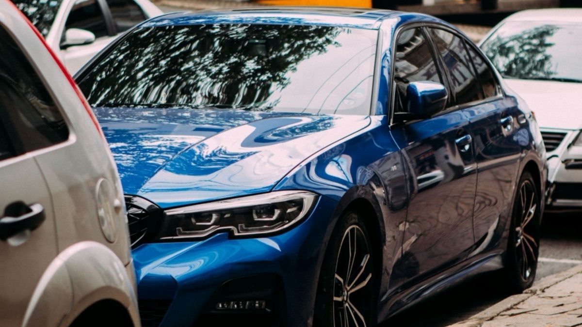 Carro azul estacionado com vidros escurecidos por película automotiva.