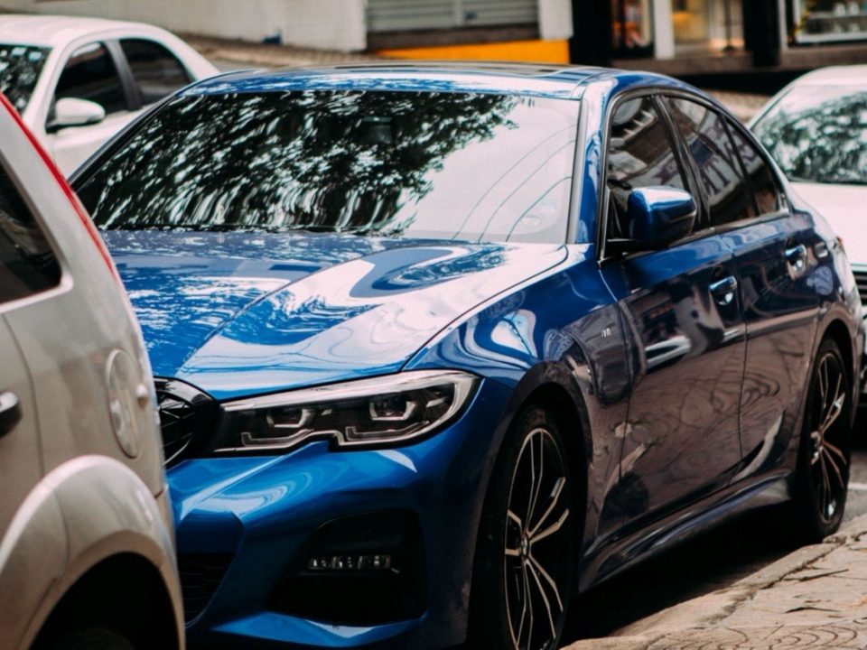 Carro azul estacionado com vidros escurecidos por película automotiva.