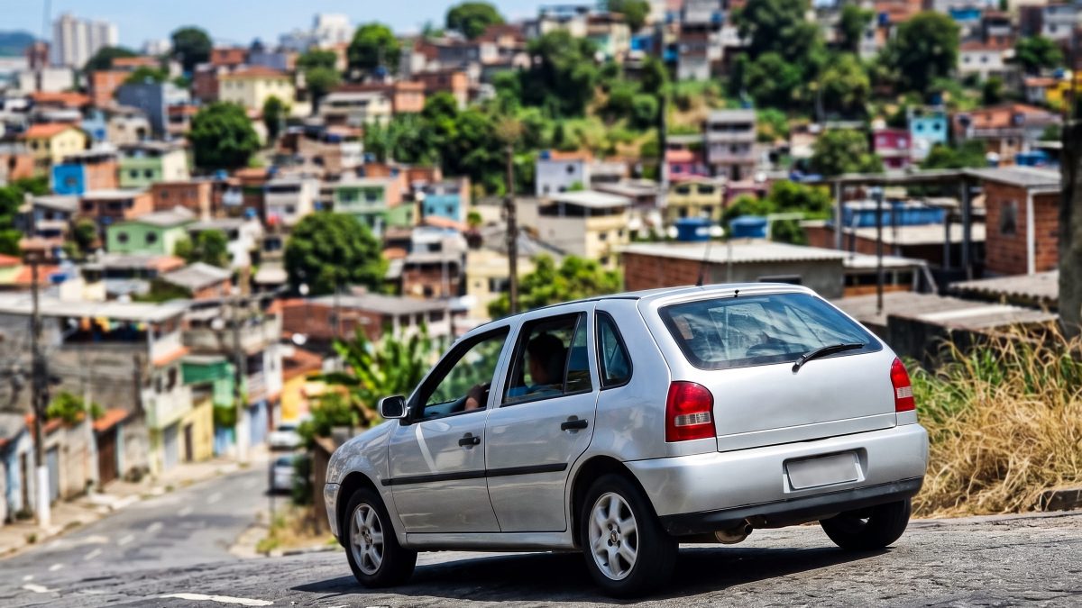 Volkswagen Gol prata descendo uma ladeira íngreme em bairro brasileiro, ilustrando o uso do freio motor.