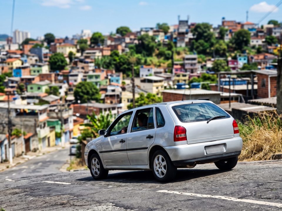 Volkswagen Gol prata descendo uma ladeira íngreme em bairro brasileiro, ilustrando o uso do freio motor.