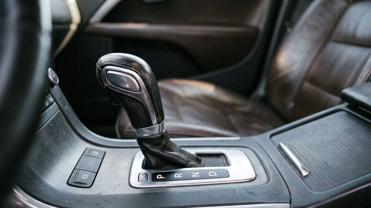 Alavanca de câmbio automático em destaque, mostrando as letras P R N D no seletor, no console central de um carro.