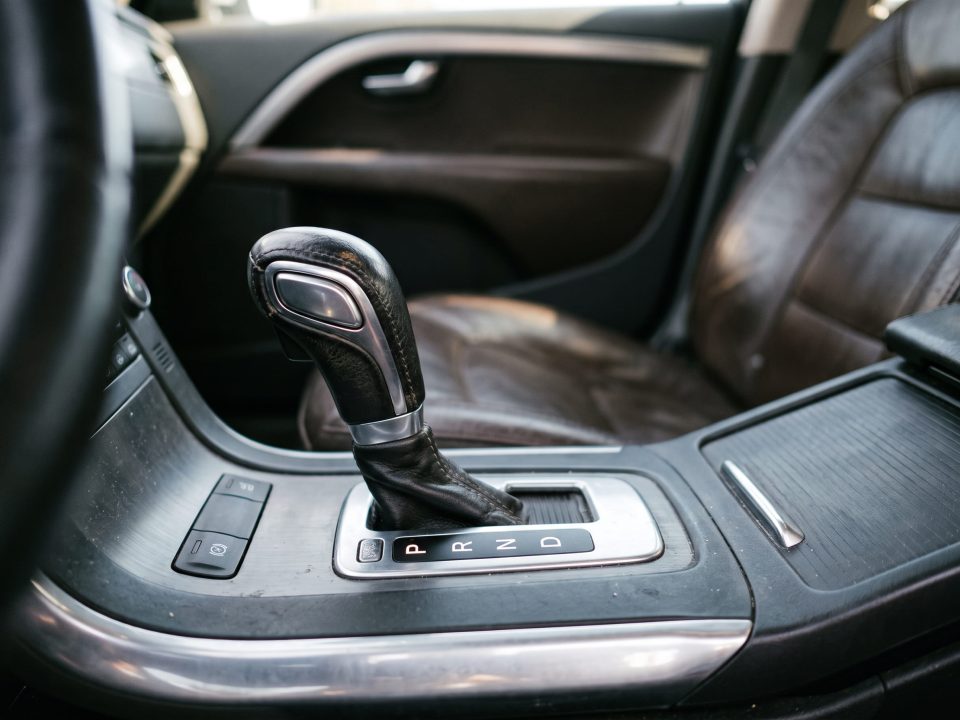 Alavanca de câmbio automático em destaque, mostrando as letras P R N D no seletor, no console central de um carro.