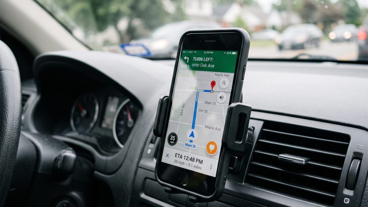 Suporte de celular fixado na saída de ar do painel do carro com smartphone exibindo rota no GPS.