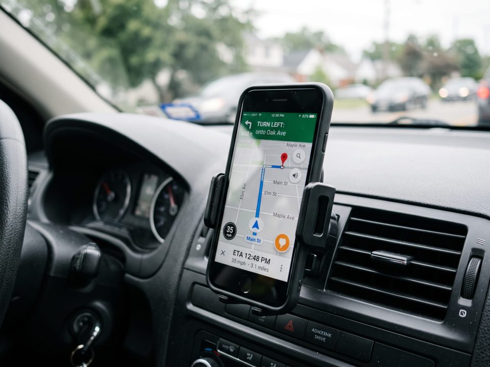 Suporte de celular fixado na saída de ar do painel do carro com smartphone exibindo rota no GPS.