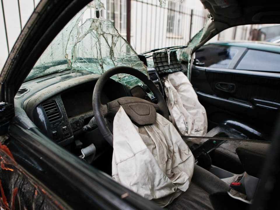 Airbags do motorista e do passageiro acionados após uma colisão, vistos de dentro do carro.