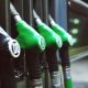 Fileira de bicos de bomba de combustível em um posto de gasolina, um preto e três verdes lado a lado.