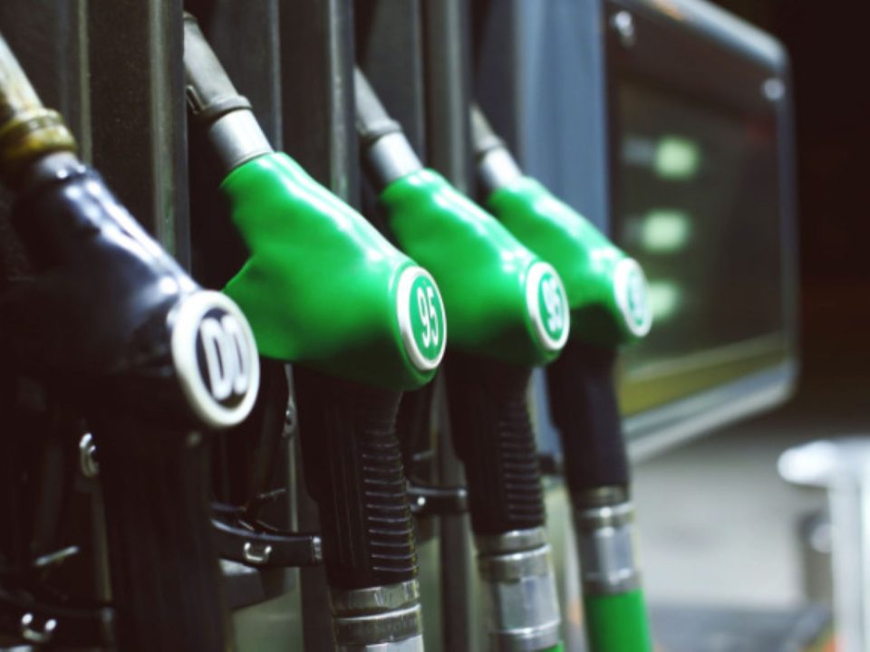 Fileira de bicos de bomba de combustível em um posto de gasolina, um preto e três verdes lado a lado.