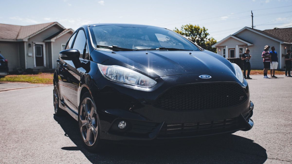 Ford Fiesta ST preto estacionado em rua residencial, com foco no para-choque dianteiro e na grade frontal.