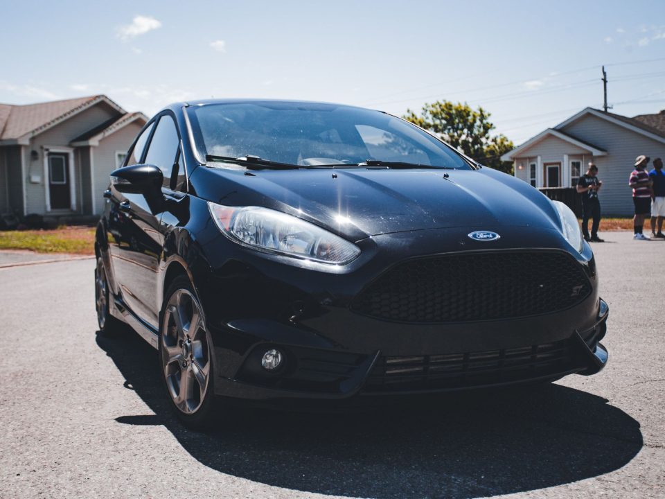 Ford Fiesta ST preto estacionado em rua residencial, com foco no para-choque dianteiro e na grade frontal.