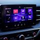 Detalhe do painel de um carro com tela de infotainment ativa entre as saídas de ar-condicionado.