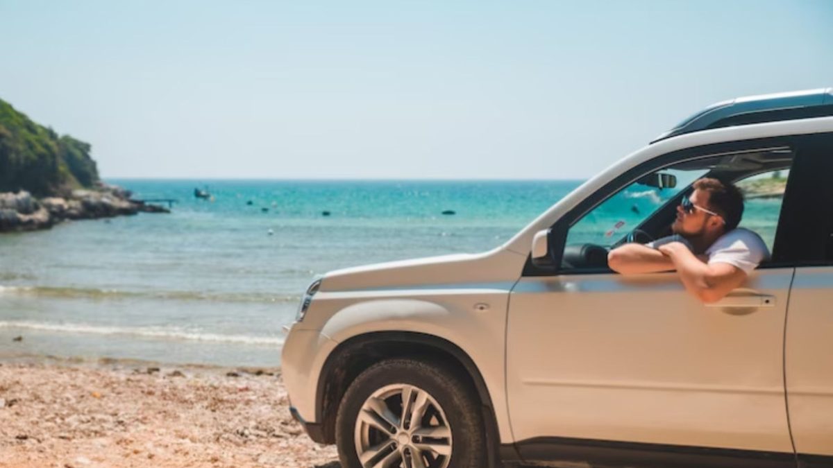 SUV prata estacionado na areia da praia, perto do mar, exposto à maresia.