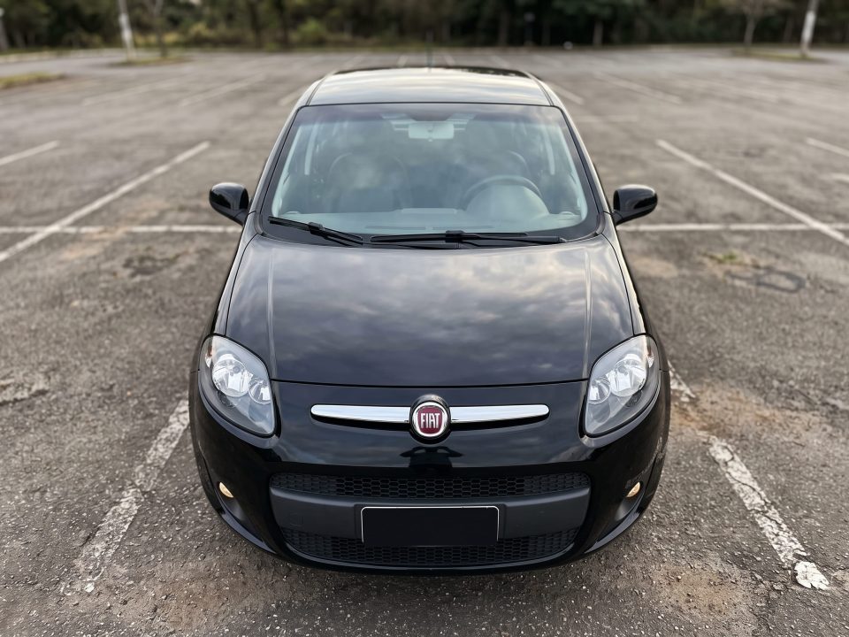 Vista frontal e elevada do capô de um Fiat Palio preto, com a grade cromada e os faróis na parte de baixo.