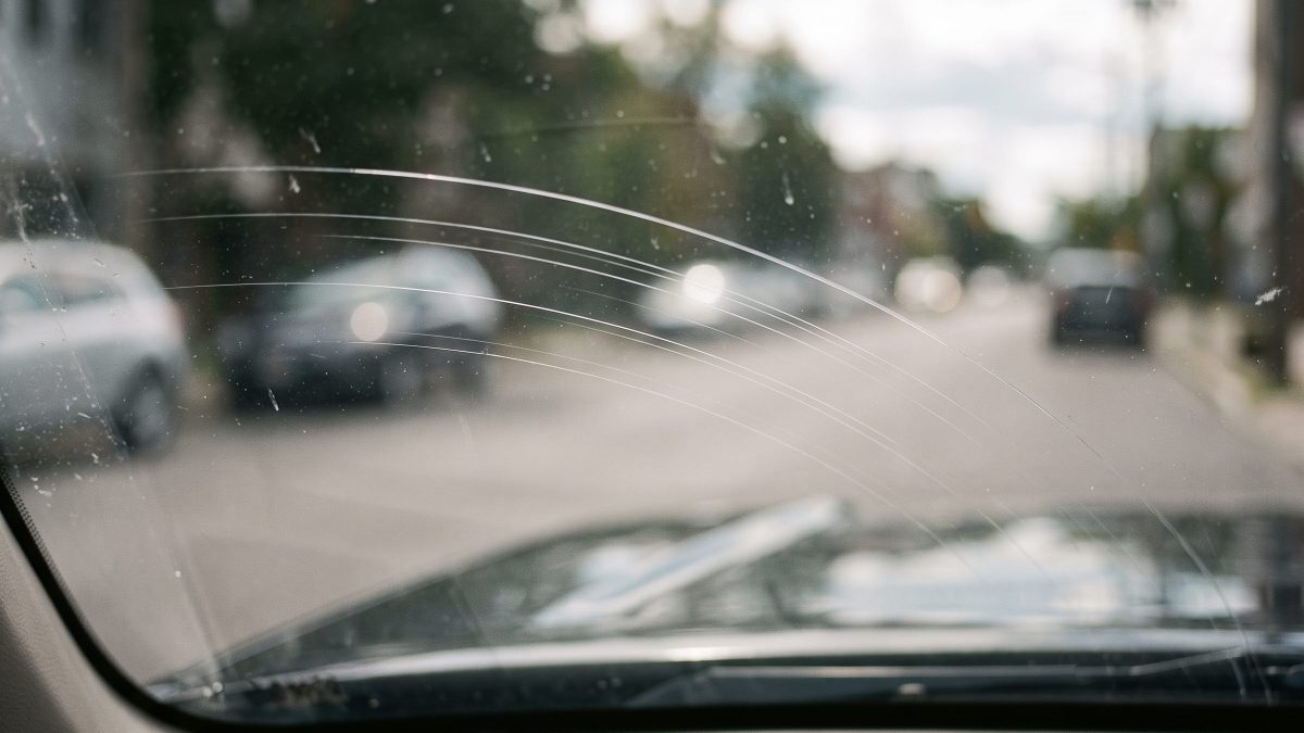 Risco fino no para-brisa visto de dentro do carro, seguindo a área de varredura da palheta.