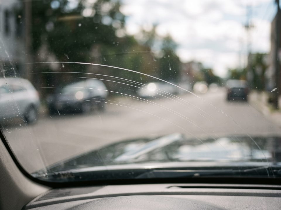 Risco fino no para-brisa visto de dentro do carro, seguindo a área de varredura da palheta.